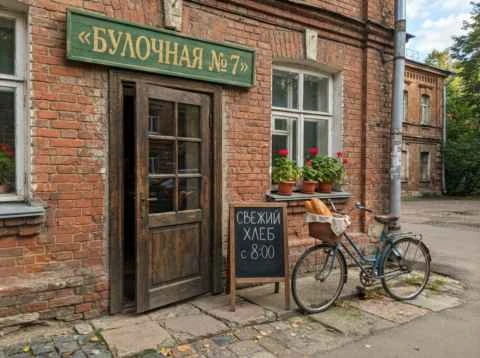 Маленькая мутная картинка: вход в булочную с вывеской, меловая доска и велосипед